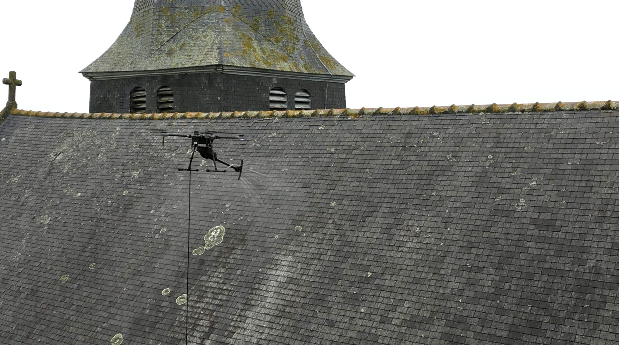 Drone en vol au-dessus de l’église de Torcé, Bretagne, pour le nettoyage de la toiture.