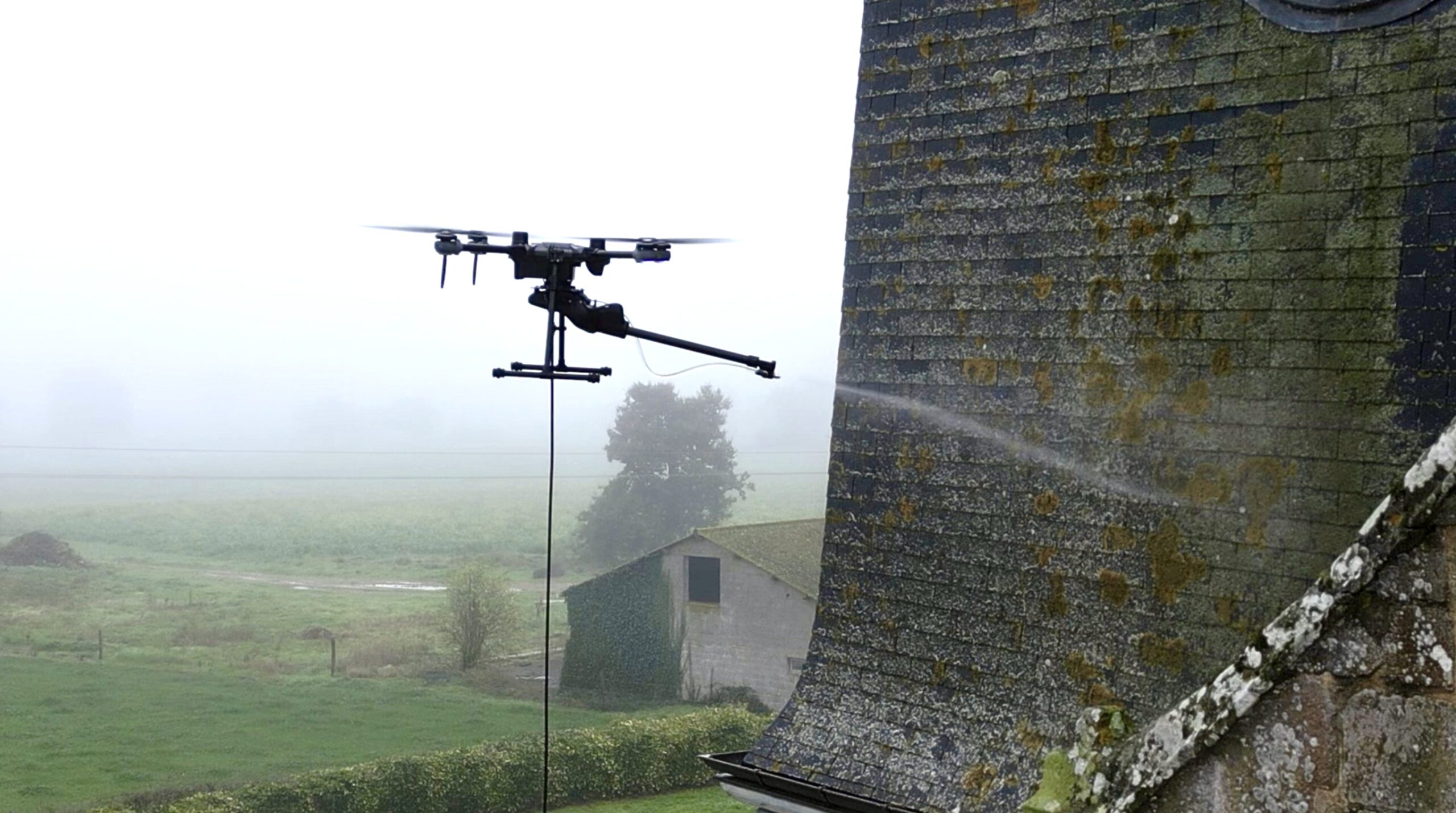 Drone pulvérisant un produit biodégradable sur la façade de l’église de Torcé en Bretagne.
